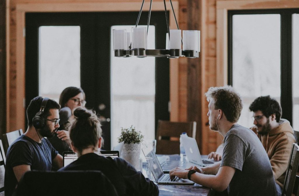 Personen sitzen an einem Tisch und arbeiten